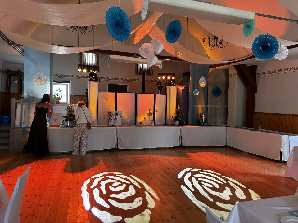 Festlich dekorierter Dorfsaal in Großkochberg mit DJ-Setup, Ambientelicht und Rosen-Gobos bei einer Hochzeit