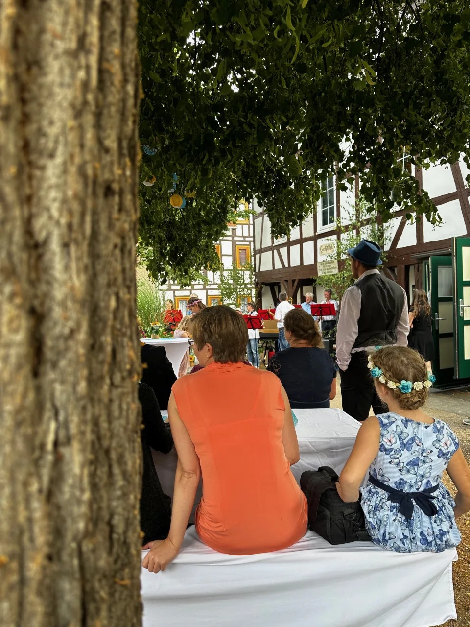 Hochzeitsgesellschaft im Freien unter einem Baum vor Fachwerkhäusern in Großkochberg