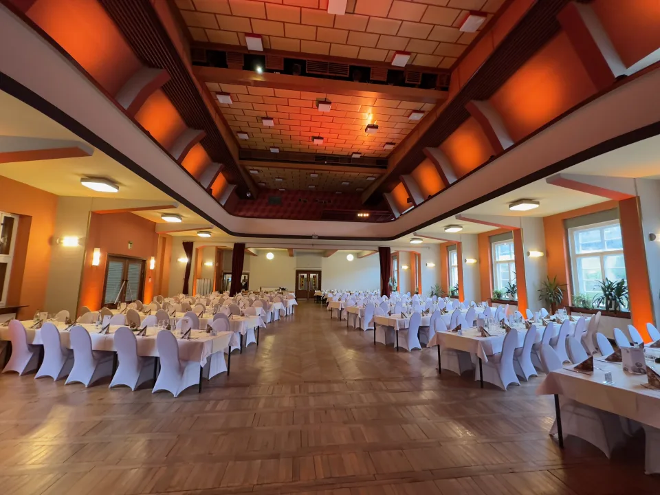 Großer roter Saal im Haus des Volkes Probstzella mit langen Festtafeln, Bauhaus-Architektur und warmem Uplight