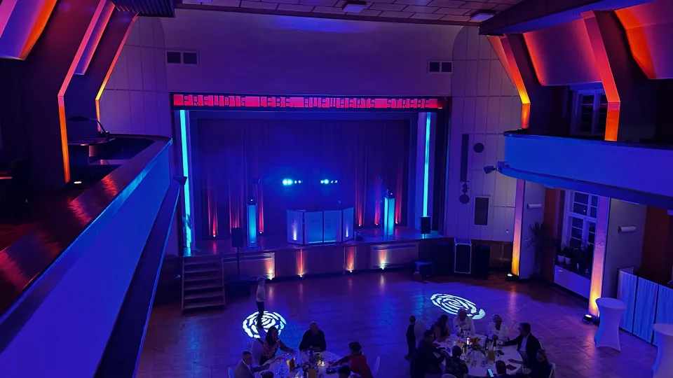 Großer roter Saal im Haus des Volkes Probstzella in blau-orangem Lichtkonzept mit Bühne und Gobos auf der Tanzfläche