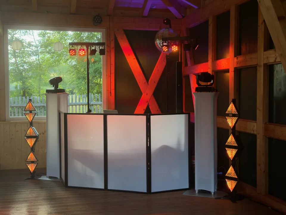 Aufgebautes DJ-Setup mit weißer Front, beleuchteten Towern und Moving Heads in der Festscheune des Landkulturhofs Glücksbringer
