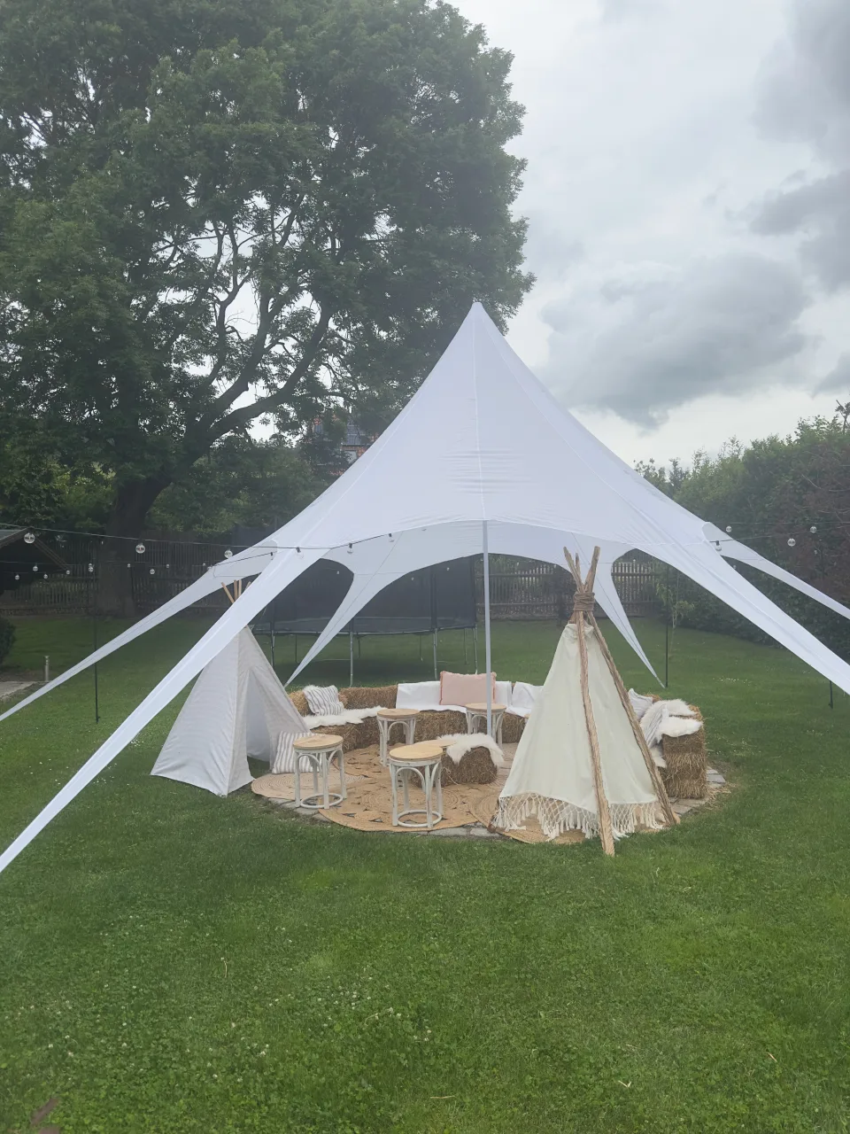 Boho-Lounge unter einem weißen Sternzelt im grünen Außenbereich des Landkulturhofs Glücksbringer